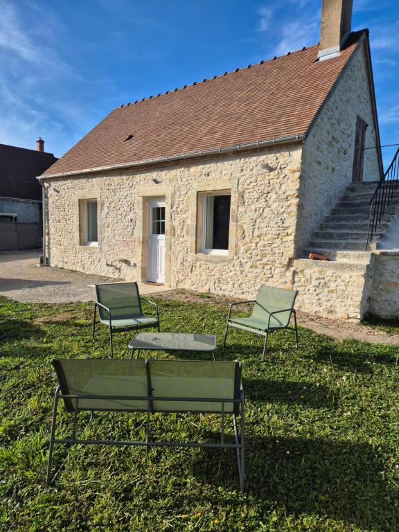 three chairs and a bench in front of a building at La P'tite Pierre in Ineuil