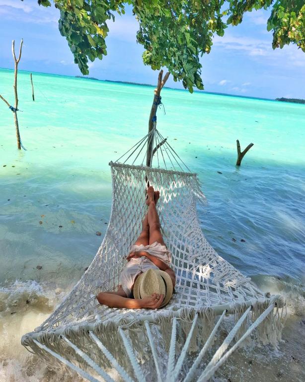 a woman laying in a hammock on a beach at Manoa Kei Boutique Villas in Letman