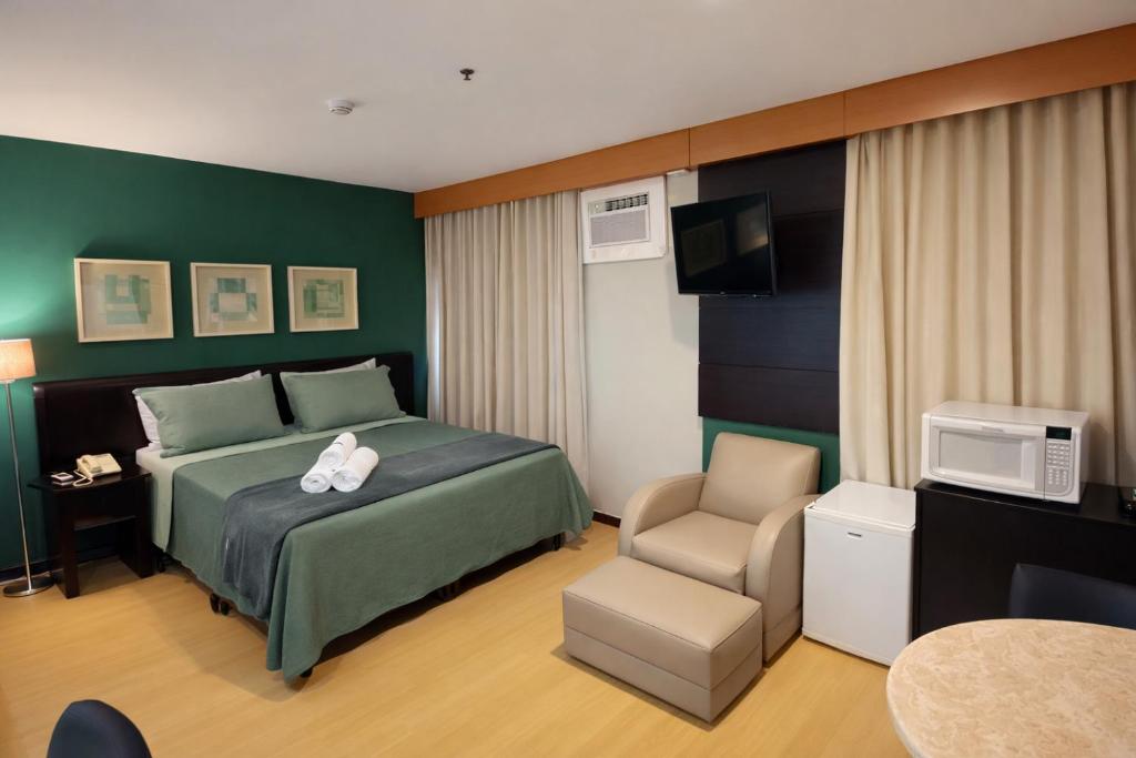 a bedroom with a bed and a tv and a chair at Flat Vila Olimpia Hotel Experience in São Paulo