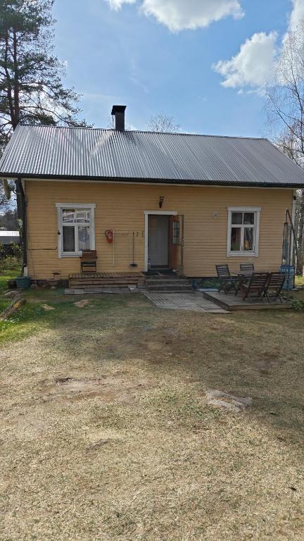 a yellow house with a metal roof and a yard at Ranta mökki in Kouvola