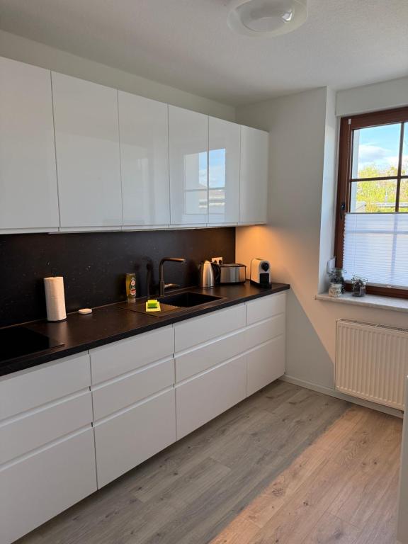 an empty kitchen with white cabinets and a window at NEU Apartment Lotta in Senftenberg