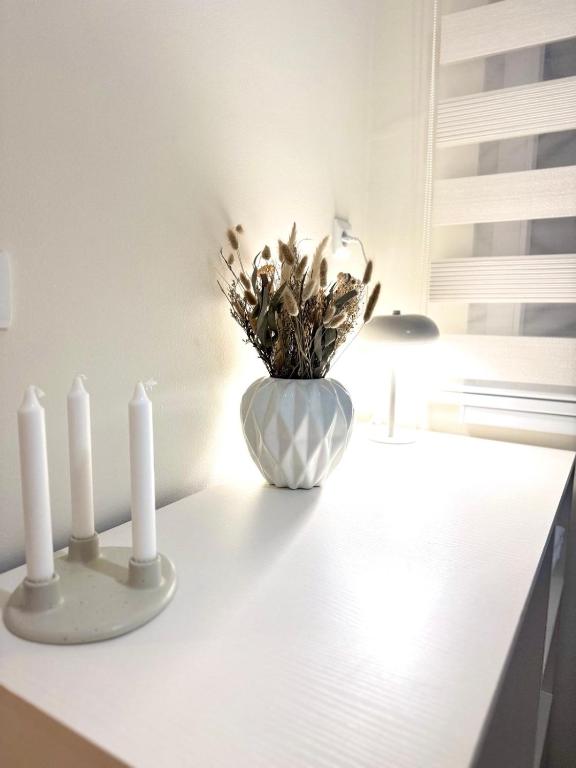 a white vase with two white candles on a counter at Sand and stone oasis in Ohrid