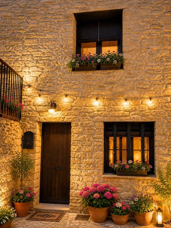 a stone building with two windows with flowers and lights at Ca la Genoveva in Montsonis