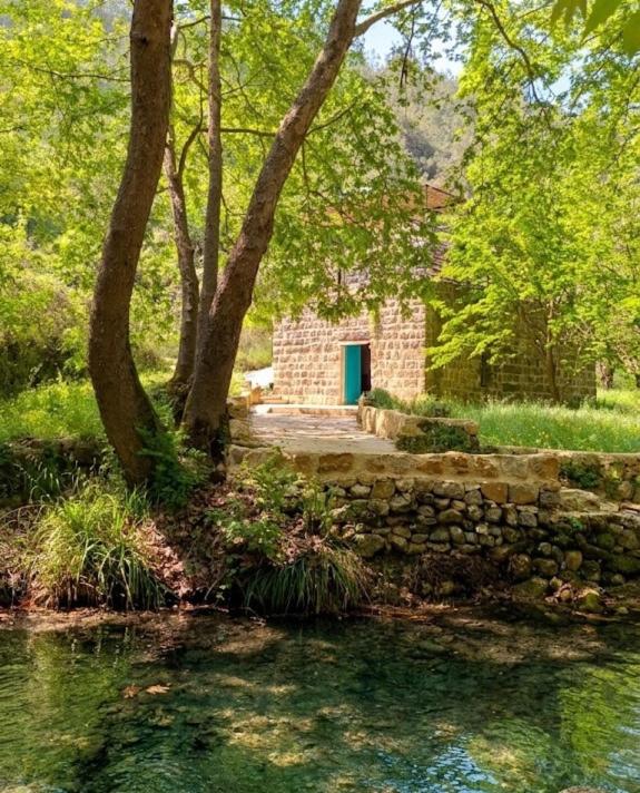 a brick building with a blue door next to a pond at Bayt Broud in Gharīfah