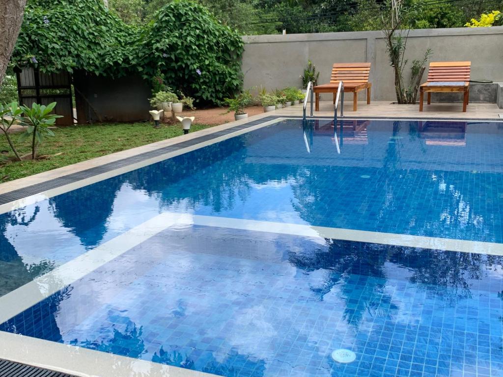 a blue swimming pool with two chairs in a yard at Summerland Residence in Udawalawe