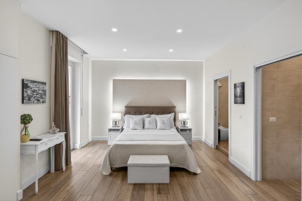 a white bedroom with a large bed and wooden floors at Pompei Luxury Suites-Near Ruins in Pompei