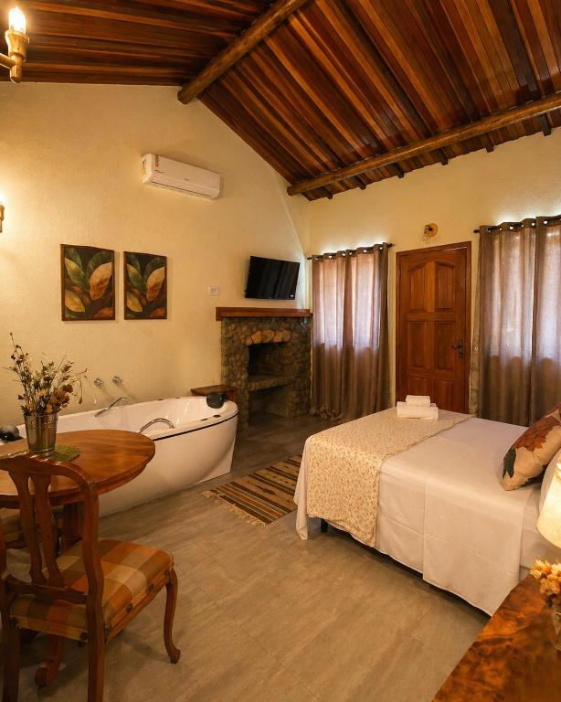 a bedroom with a tub and a bed and a bathtub at Refúgios de Mauá - Chalé Jardins de Maria in Visconde De Maua
