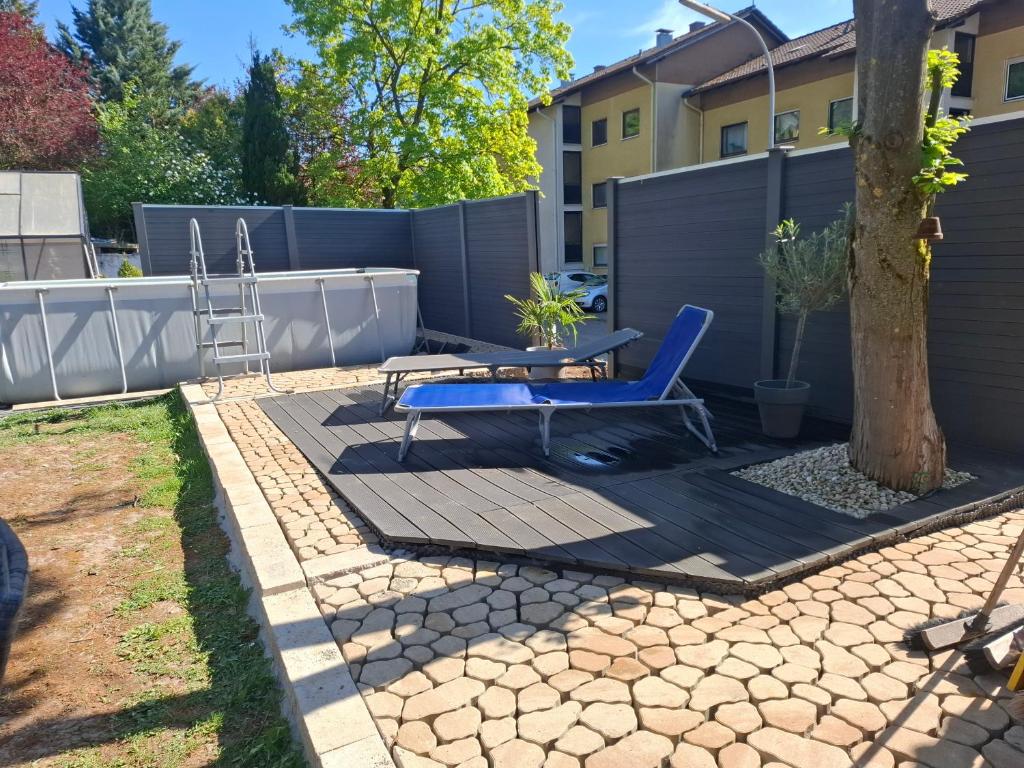 a patio with a blue chair and a table and a tree at Dörrs vacation home with heated pool and garden in Weißbach