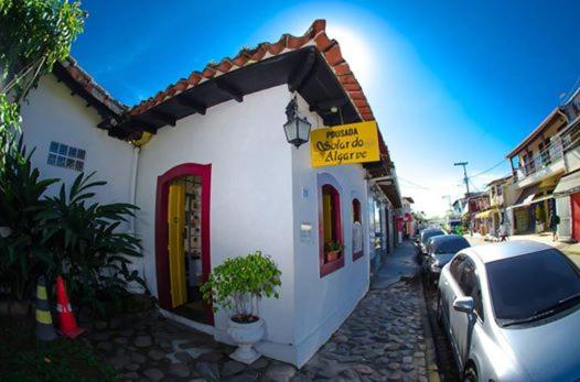 a small white building with a car parked next to it at Pousada Solar do Algarve em Paraty há 5 minutos do Centro Histórico in Paraty