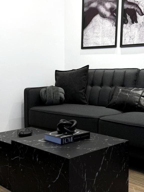 a living room with a black couch and a table at The Lithos Loft Kyma in Ayía Marína
