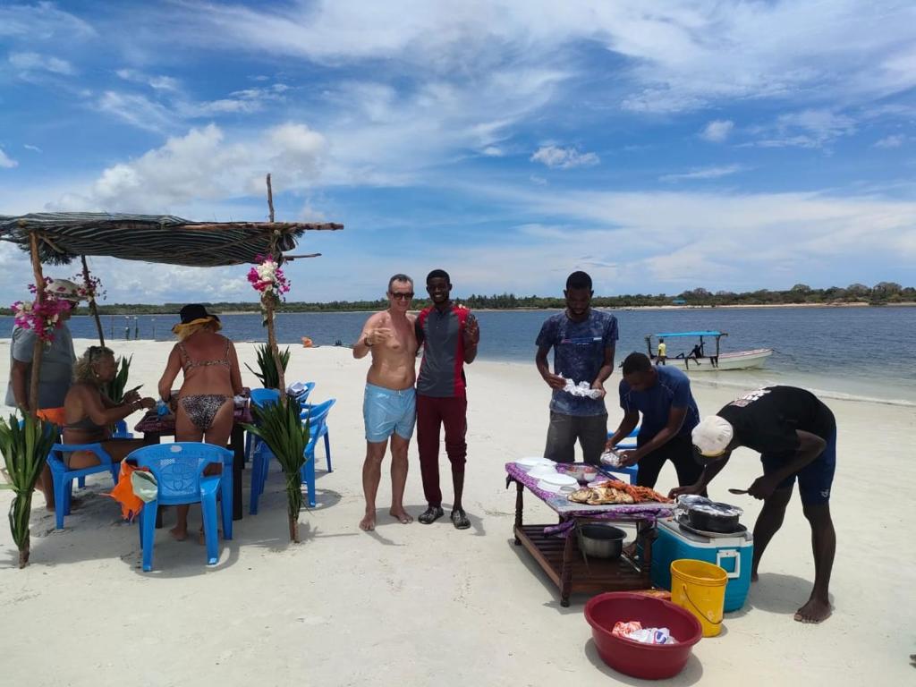 a group of people standing on the beach at Funzi Beach Resturant in Funzi