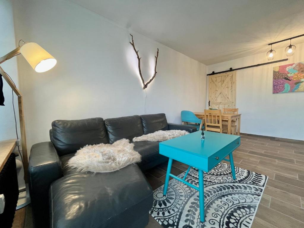 a living room with a black leather couch and a blue table at Maria Altreichenau in Neureichenau