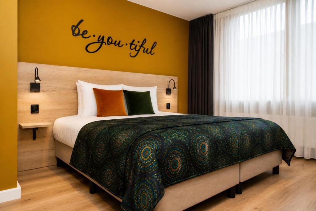 a bedroom with a bed with a be you find sign on the wall at Hotel Onder De Linden in Roden