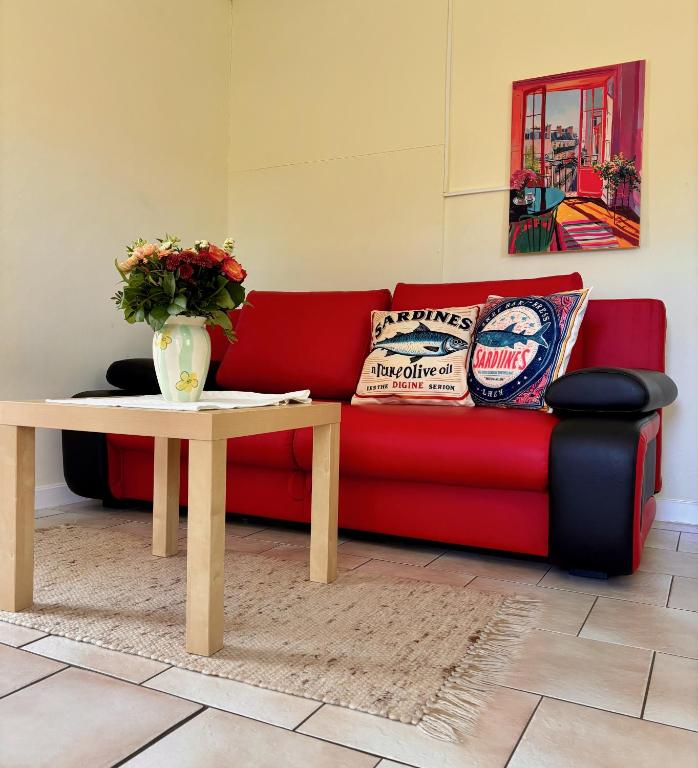a red couch with a table and a vase of flowers at Hamburg Living Hub in Pinneberg