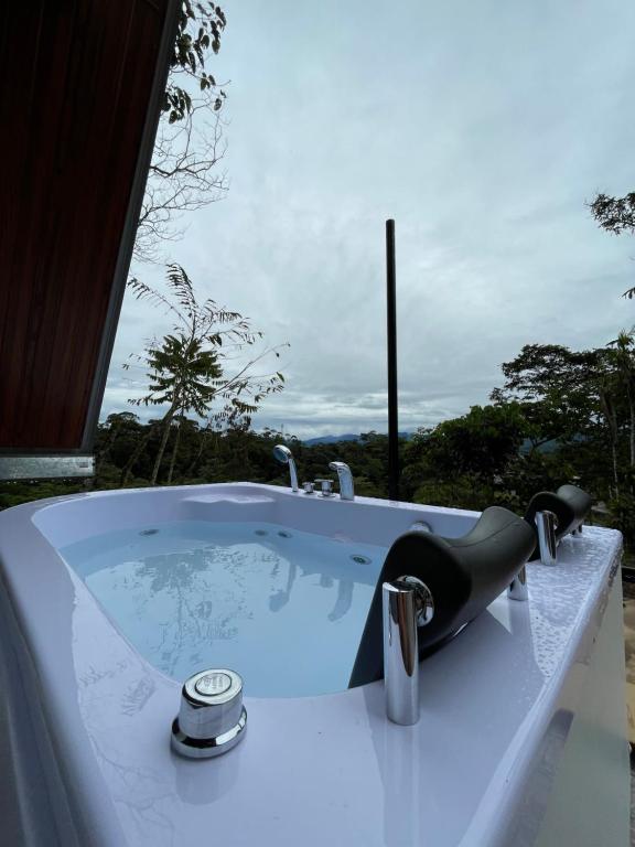 a jacuzzi tub with a view of the forest at Refugio de la niebla puyo glamping in Puyo