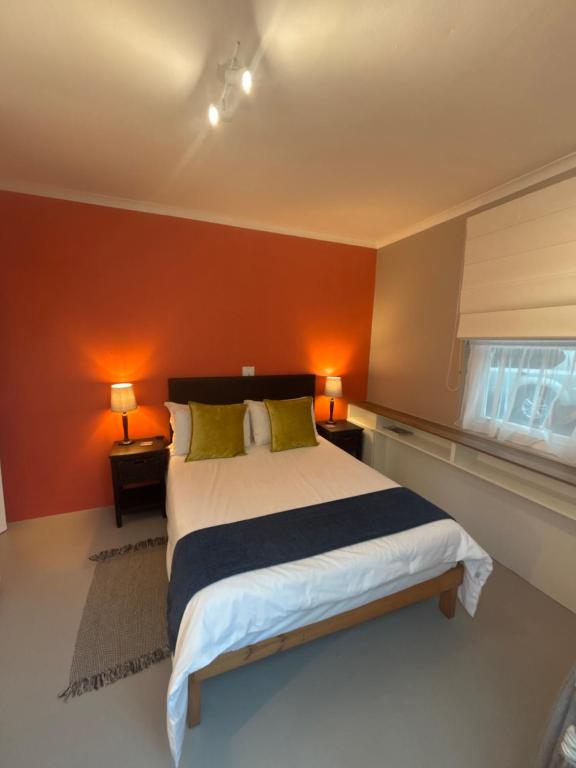 a bedroom with a large bed with orange walls at The Muizenberg Muse in Muizenberg