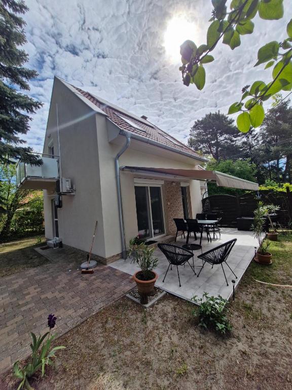 a small white house with chairs and a patio at Fenyves Ferienhaus 1 **** in Balatonfenyves