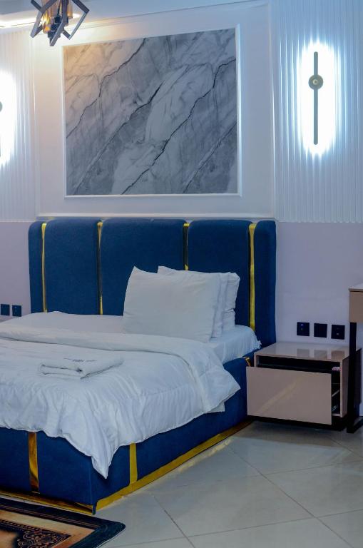 a blue bed in a room with a cross on the wall at Henry George Hotel Ltd in Idimu