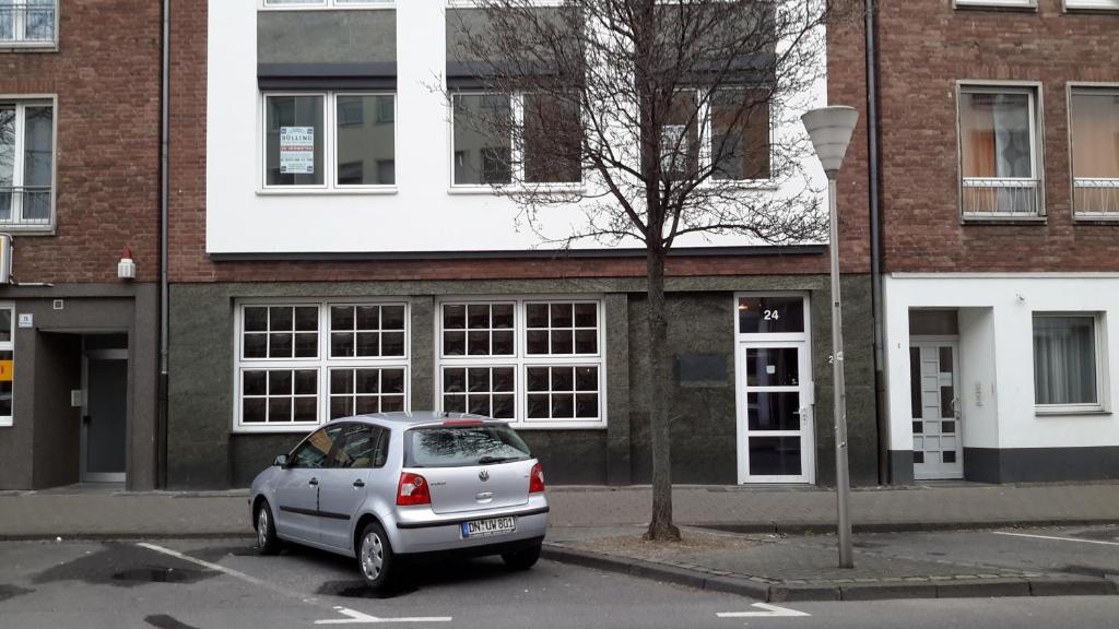 ein silbernes Auto, das auf einem Parkplatz vor einem Gebäude parkt in der Unterkunft Apartment am Kaiserplatz in Düren - Eifel