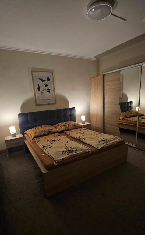 a bedroom with a bed with two lamps and a mirror at Lotti Apartman in Békéscsaba