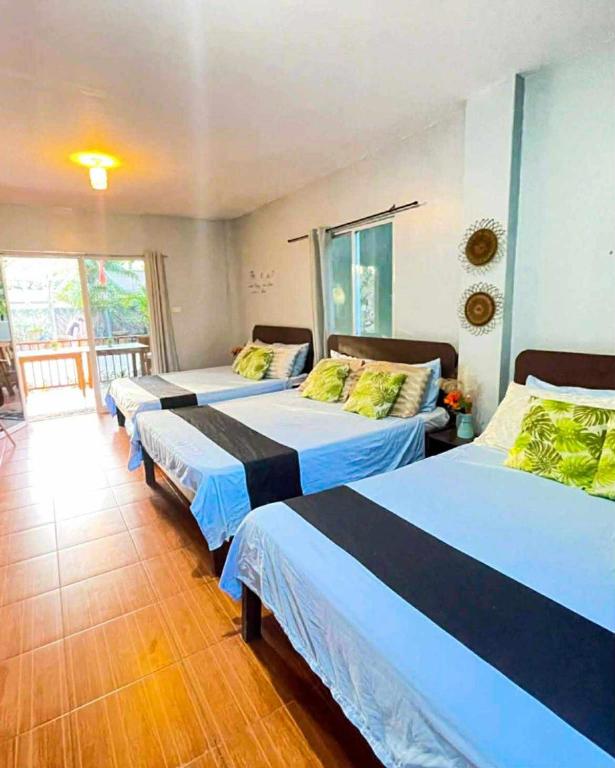 a room with three beds and a balcony at Marias's Inn in Pooc