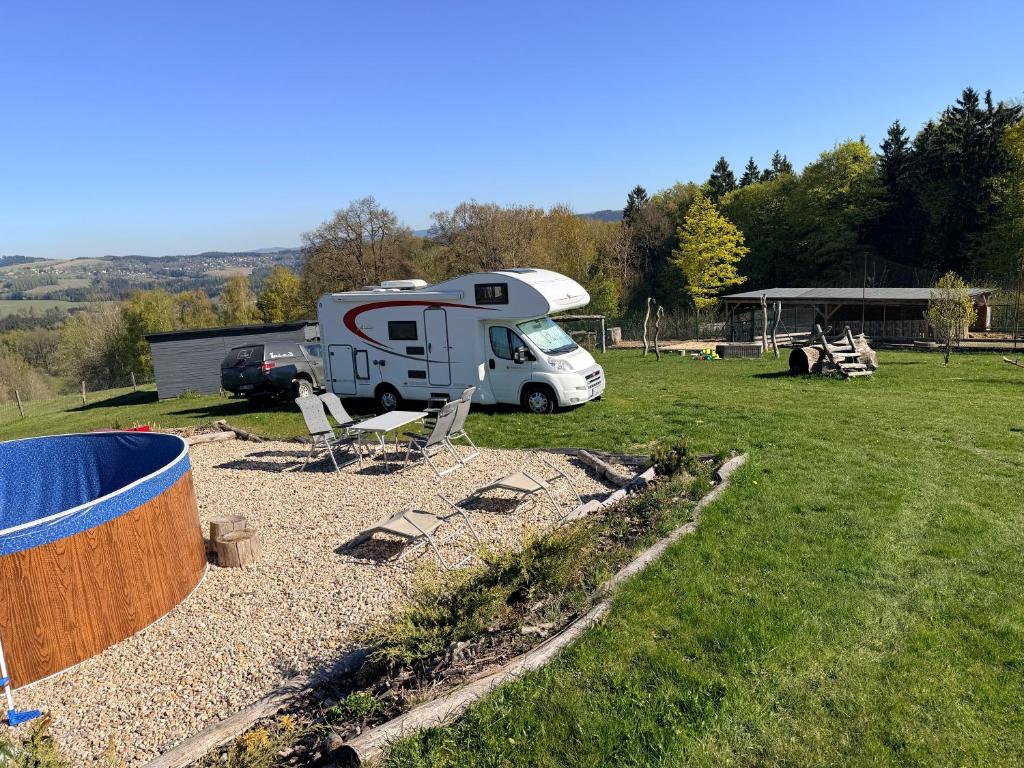 a rv parked in a field with chairs at Obytňák Bohoušek in Pulečný