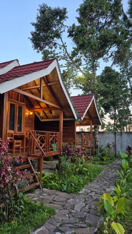 a wooden cabin with a porch and a stone walkway at Arsilahomestay in Tetebatu