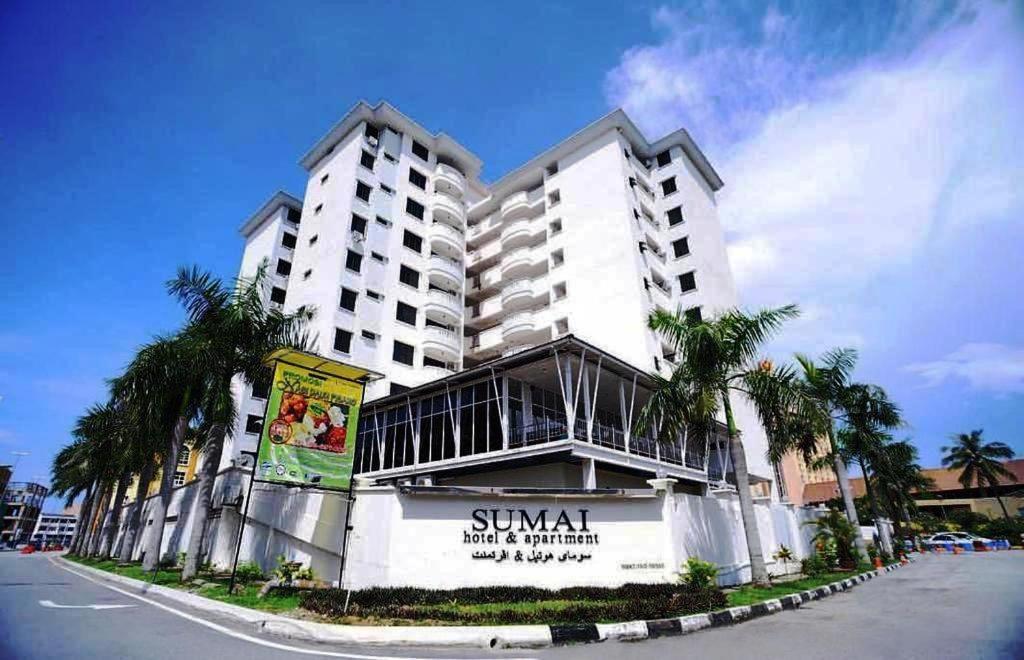 duży biały budynek z palmami przed nim w obiekcie Sumai Hotel Apartment w mieście Kuala Terengganu