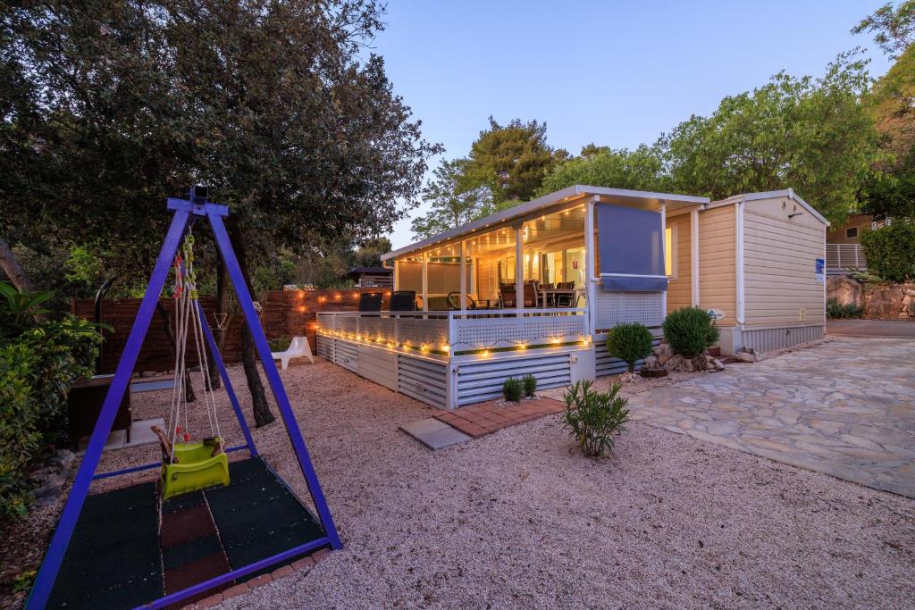 a small house with a swing and a playground at ESTRADA MOBILE HoME in Biograd na Moru