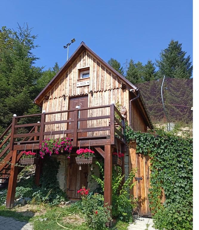 a wooden house with a deck and flowers on it at Domek MIŚ Na Stoku in Tylicz