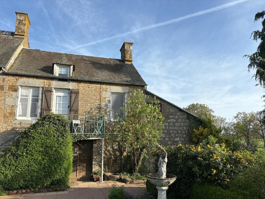 an old brick house with a statue in front of it at 11 Steps Rustic Charming Flat in Normandy in Aubusson