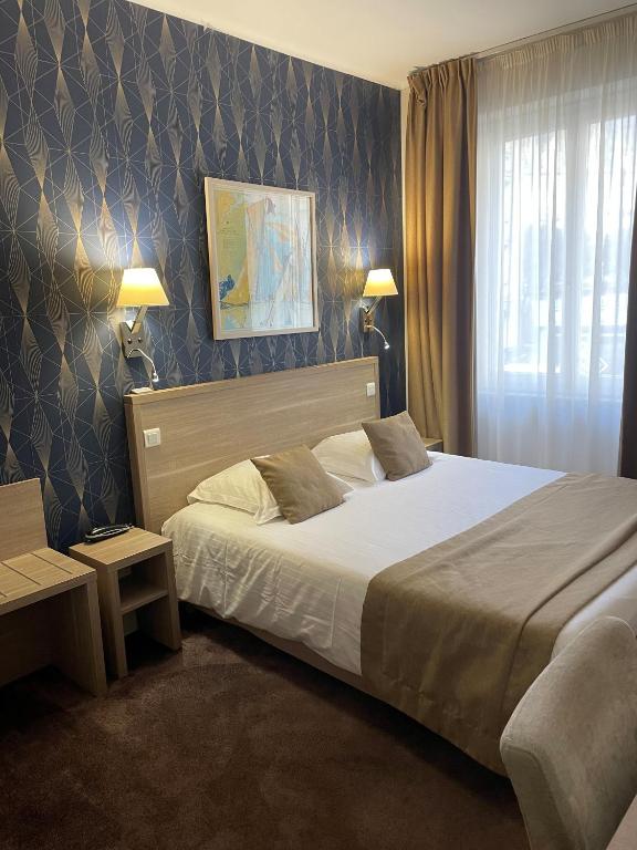 a bedroom with a large bed and a window at Hotel Ajoncs d'Or in Saint Malo