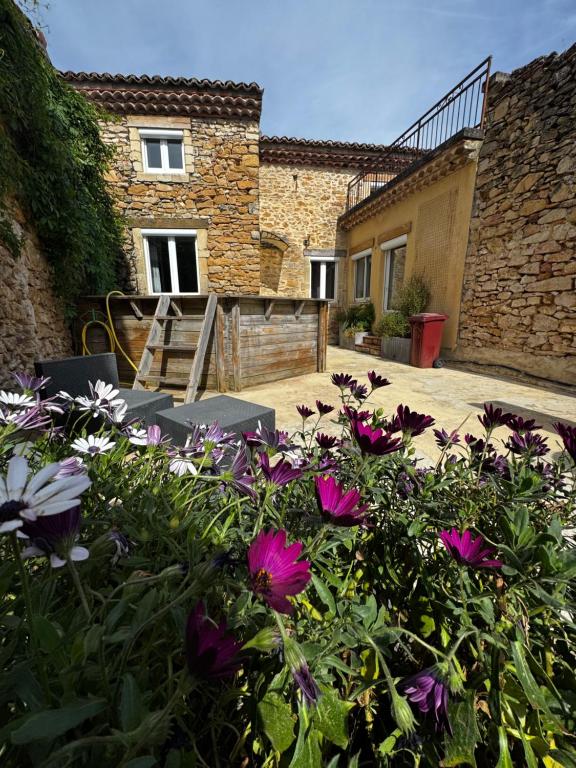 a garden with flowers in front of a building at Maison de Village 4 chambres in Sabran