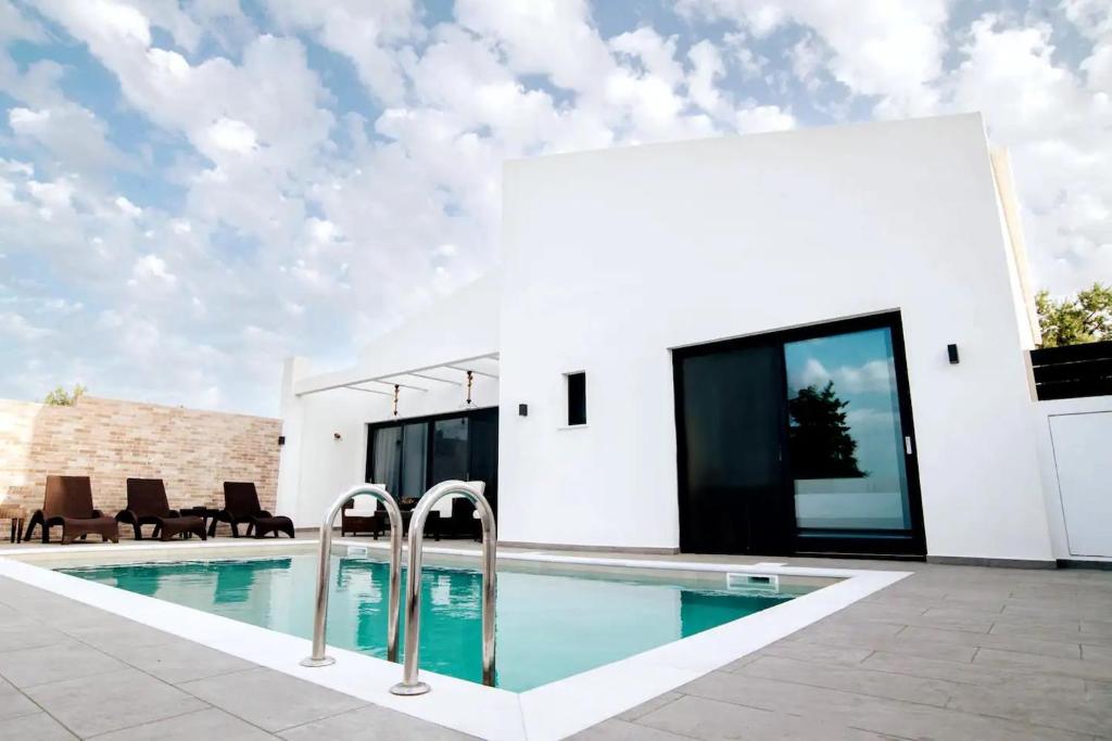 a white house with a swimming pool in front of it at Villa Etoile in Áyios Kírikos