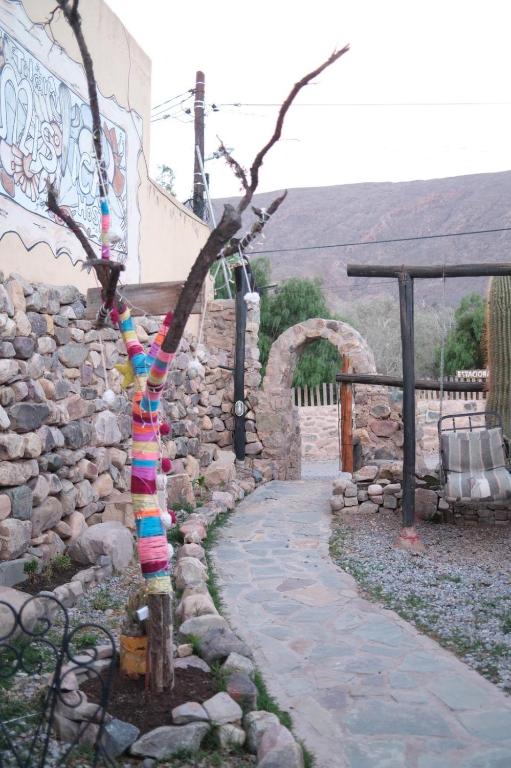 a tree wrapped in colorful ribbons next to a stone wall at Tilcara Mistica Hostel in Tilcara
