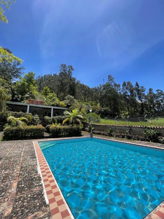 a swimming pool in front of a house at Ecohotel Naranjos in Jenesano