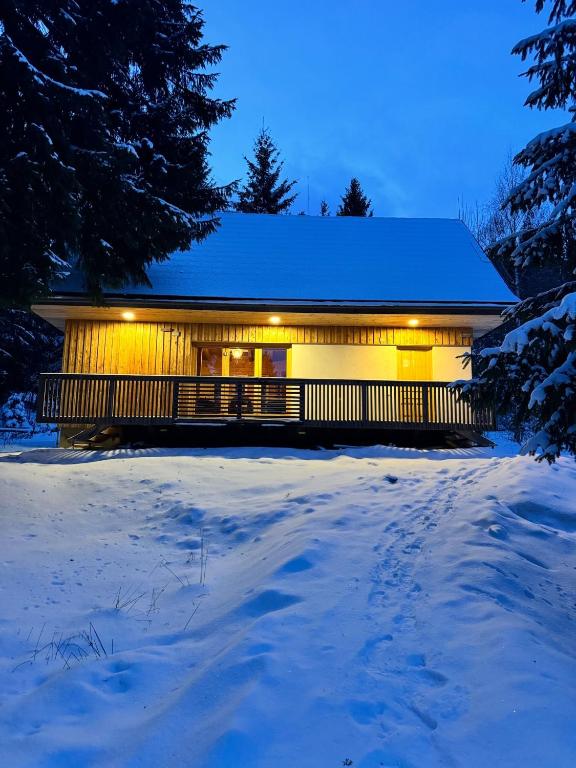 a house in the snow with lights on it at Hargitaház Mountain House in Harghita-Băi
