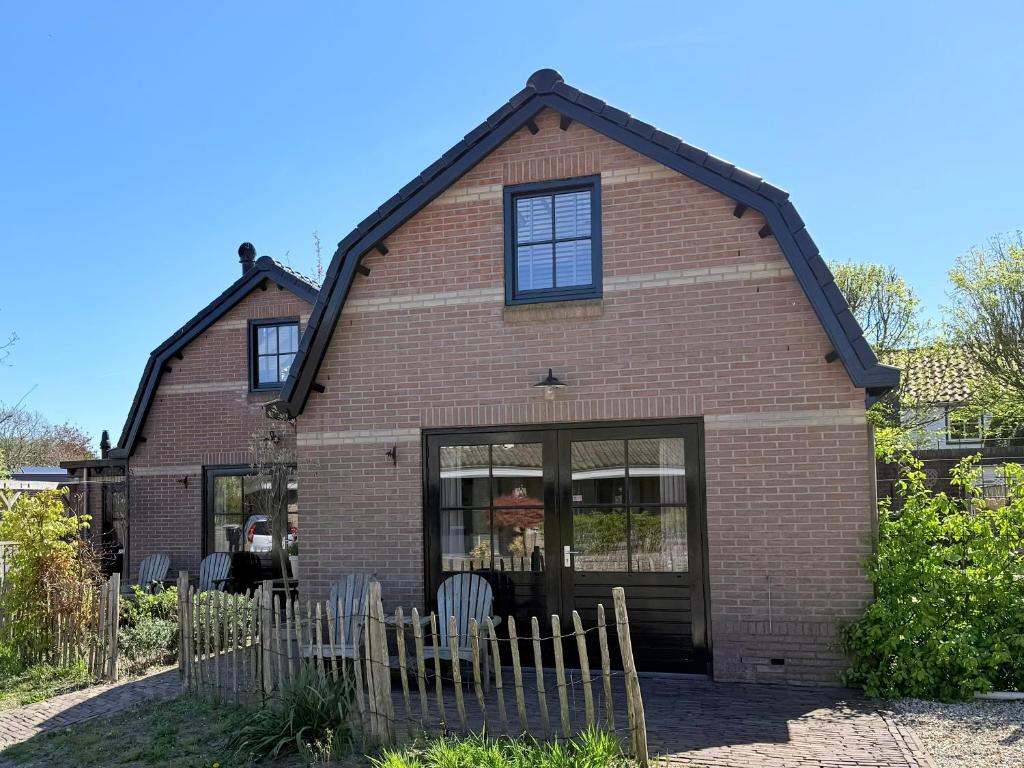 a brown brick house with windows and a fence at Tuinderswoningen Bosrijk en Zeerijk op 100m van bos en duin in Heemskerk