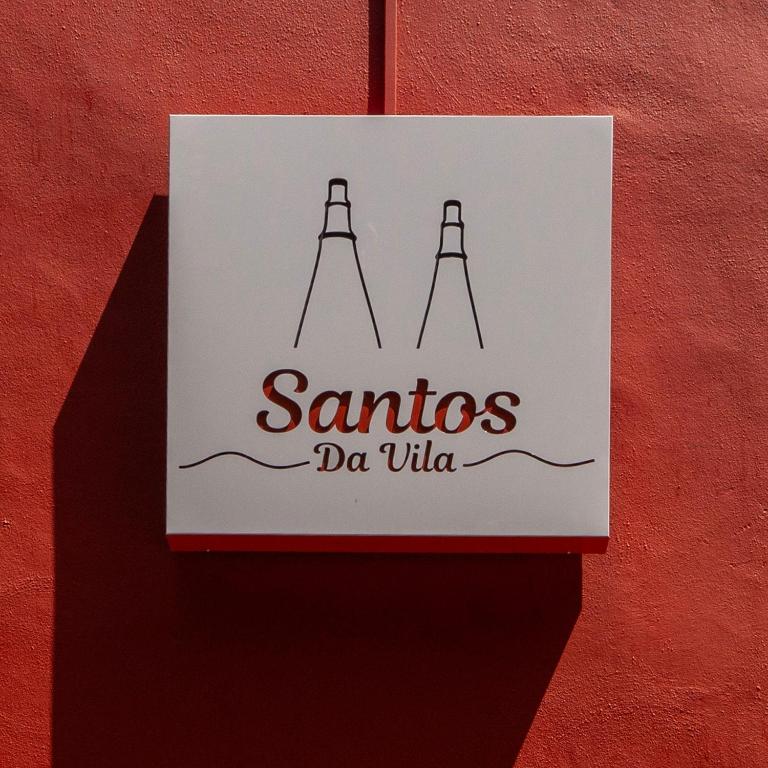 a sign hanging on a red wall with the name santos da viola at Santos da Vila in Sintra