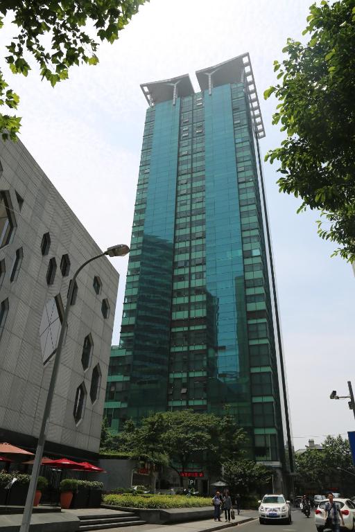 Shanghai Cosmo World Union Service Apartment في شانغهاي: مبنى زجاجي طويل القامه امامه ناس