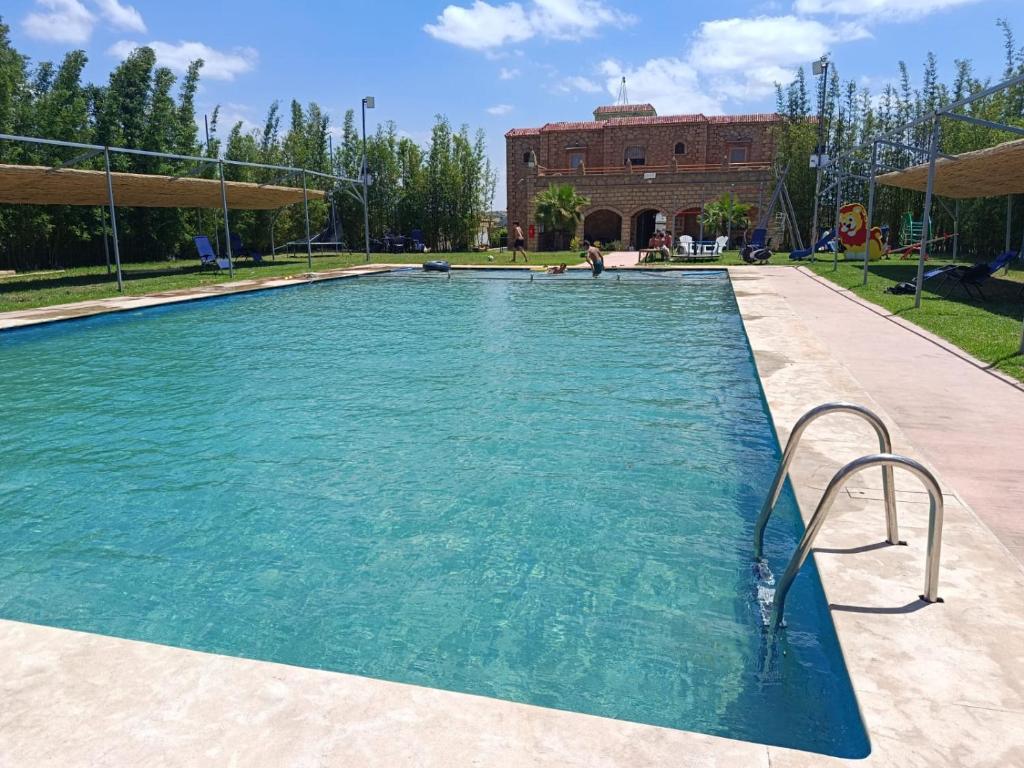 a swimming pool with blue water in a park at Villa Sun and Chill, Ferme d'hôtes familiale avec piscine animée, restaurant et jardin près de Safi in Safi
