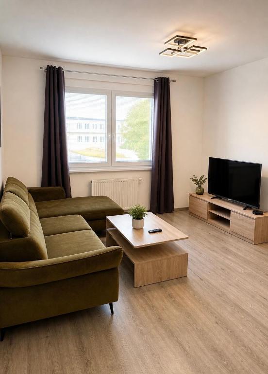 a living room with a couch and a flat screen tv at Apartmán centrum BB s balkónom a parkovaním in Banská Bystrica