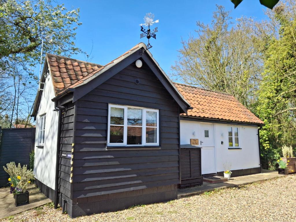 a black and white tiny house with a cross on the roof at The Lily Pad, Eye, Suffolk in Thornham Magna