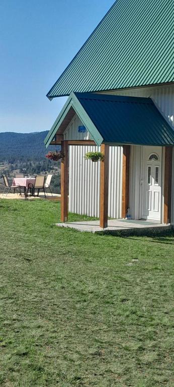 a building with a blue roof on a field of grass at MANN House in Ninkovići