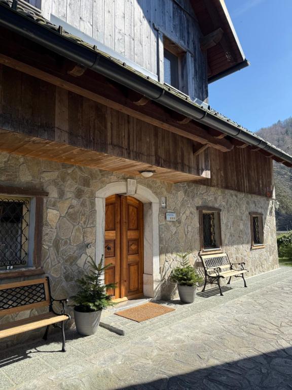 a building with a wooden door and benches in front at 4 Elements Resort Bled in Bohinjska Bela