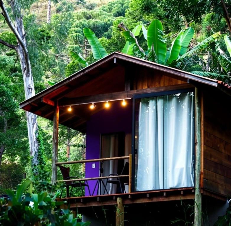 a cabin in the forest with a balcony and lights at Chalé beija flor in Paraisópolis