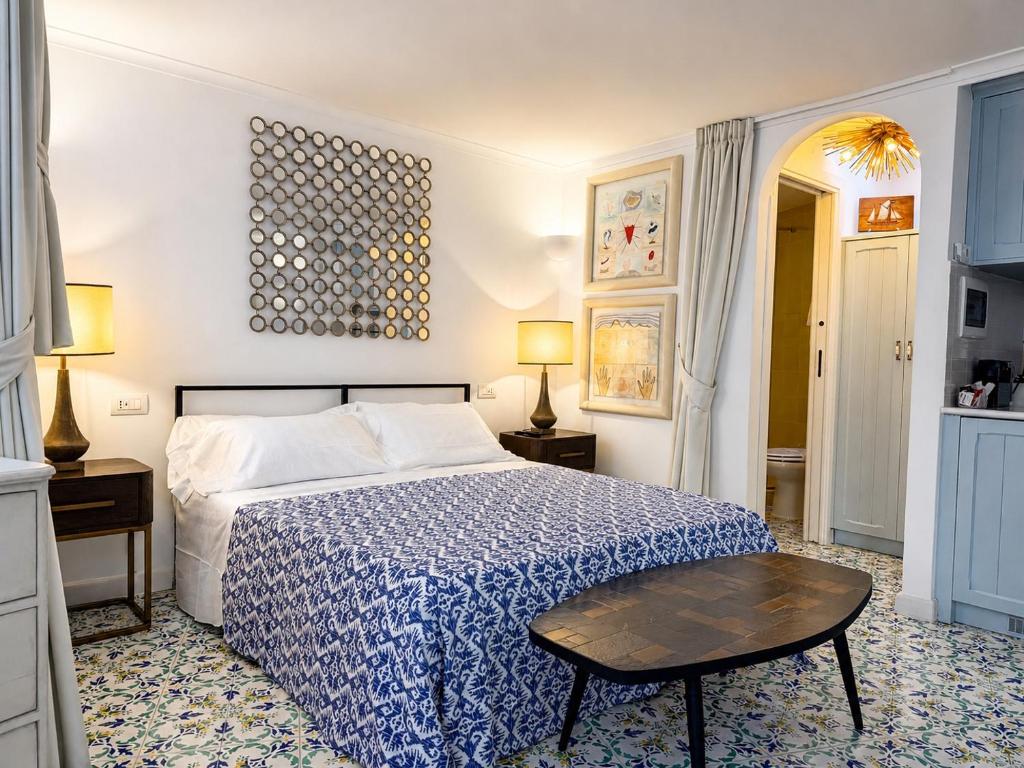a bedroom with a blue and white bed and a table at Villa Sain Charming Suite in Anacapri