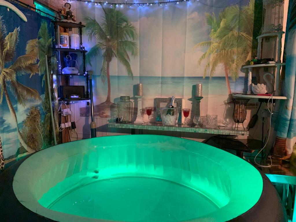 a green tub in a room with a wall with palm trees at Bonnye's guest house in Ramsgate