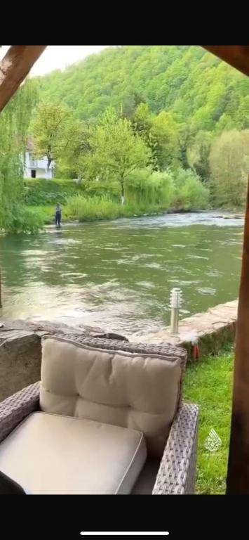 a couch sitting on a porch next to a river at Apartman Vrbas in Donji Vakuf