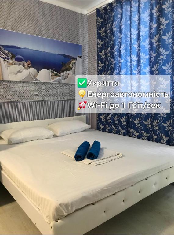 a bed with two blue slippers on top of it at Santorini Odesa in Odesa